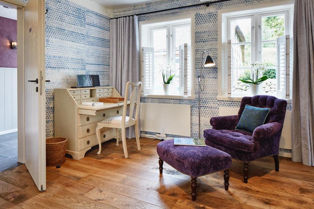 uma sala de estar com uma cadeira e uma secretária em Landhaus Altes Pastorat em Süderende
