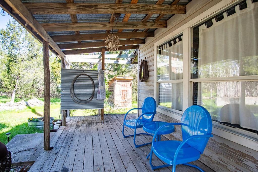 two blue chairs and a table on a porch at A Quaint Countryside Tiny Home - Outhouse & Outdoor Shower Included in San Marcos