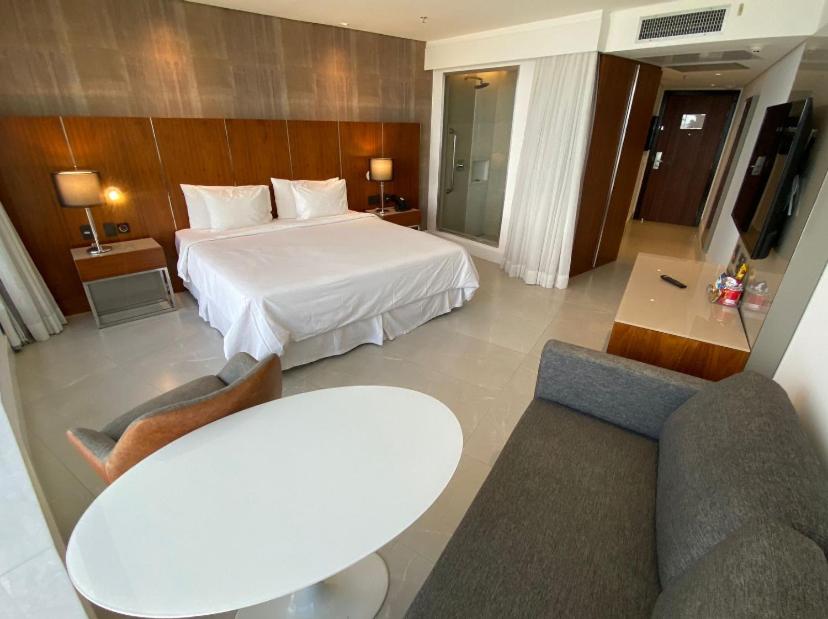 リオデジャネイロにあるApart Hotelのベッド、テーブル、椅子が備わるホテルルームです。