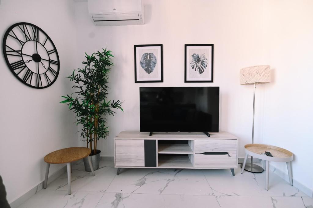 ein Wohnzimmer mit einem TV an einer weißen Wand in der Unterkunft Bright 2 Bedroom flat in Sliema! in Sliema