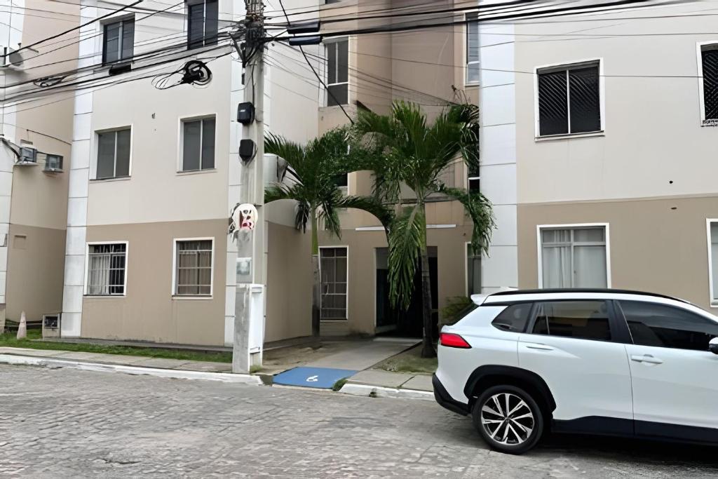 un coche blanco estacionado frente a un edificio en Aconchego Urbano: Espaçoso C/Ar en Feira de Santana