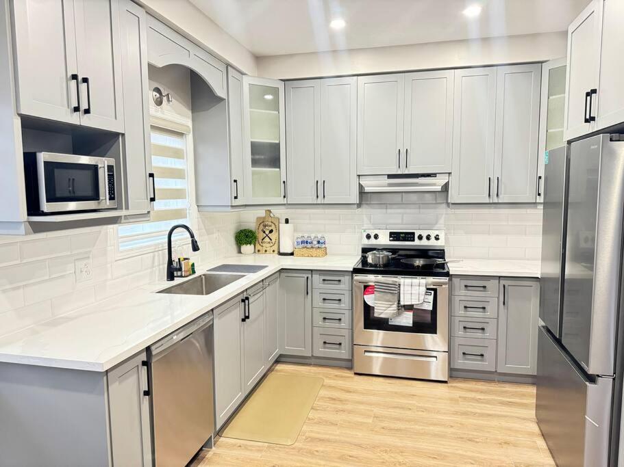 una cocina con armarios blancos y electrodomésticos de acero inoxidable en Luxury Private home near Sunrise Shopping Complex en Kitchener