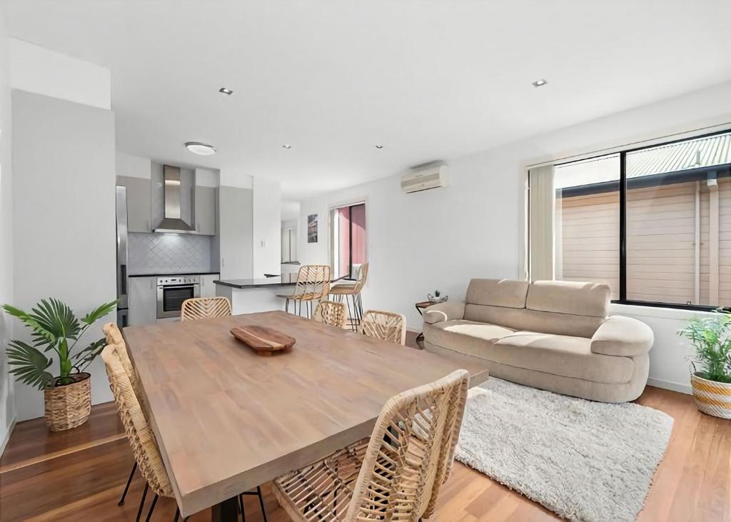 a living room with a wooden table and a couch at Golfers Dream managed by Batemans Bay Accom in Batemans Bay