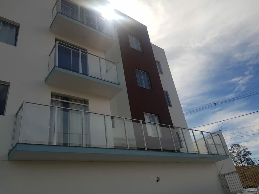 a building with a balcony with the sun in the sky at Apartamento inteiro com garagem em Diamantina/MG in Diamantina
