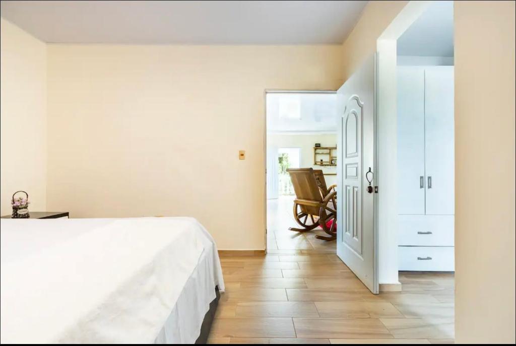 1 dormitorio con 1 cama blanca y 1 silla en apartamento EL CORAL en Río San Juan