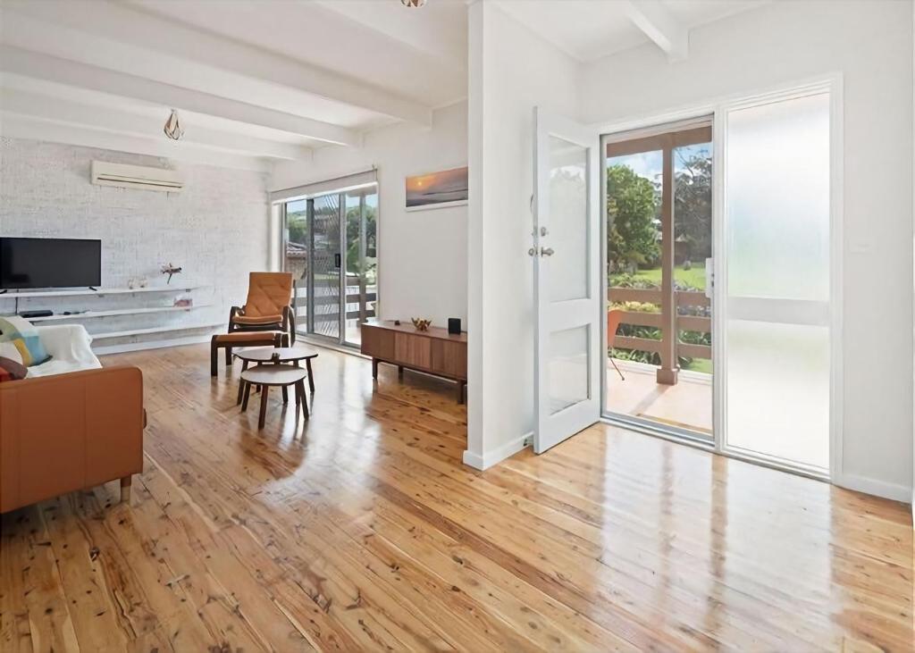 a living room with white walls and a hard wood floor at Surf Beach Retreat in Surf Beach
