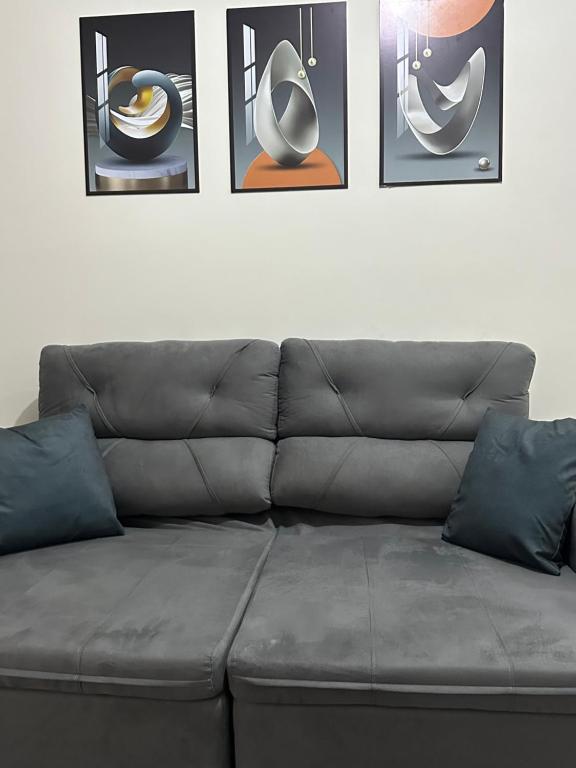 a couch in a living room with pictures on the wall at Residencial Paraiso in Sinop