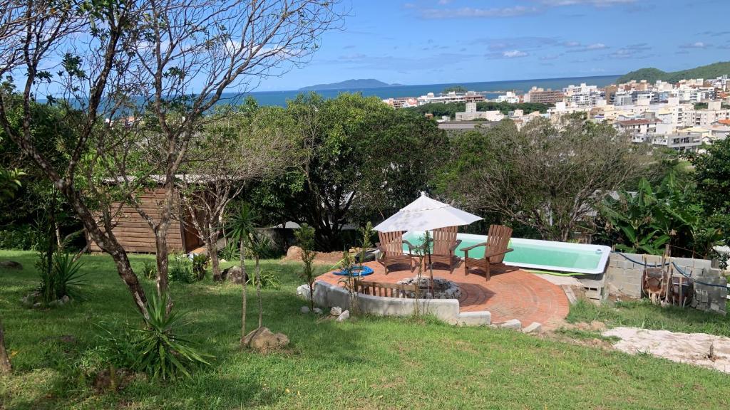 un patio trasero con piscina y una mesa con sombrilla en Recanto da Vila - Chalé 01, en Governador Celso Ramos