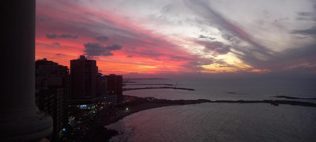 a sunset over the ocean with a city and buildings at Stunning Sea View Flat (One Bed Room)Entire Place in Alexandria