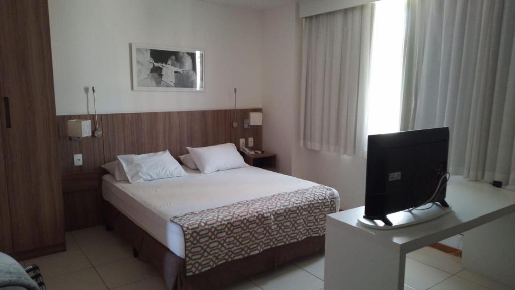 ein Hotelzimmer mit einem Bett und einem TV in der Unterkunft Flat Completo no Soho Promenade - Wi-Fi e NF in Campos dos Goytacazes