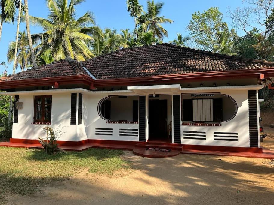 a white house with a black roof and palm trees at soha bungalow-escape the city in Kurunegala