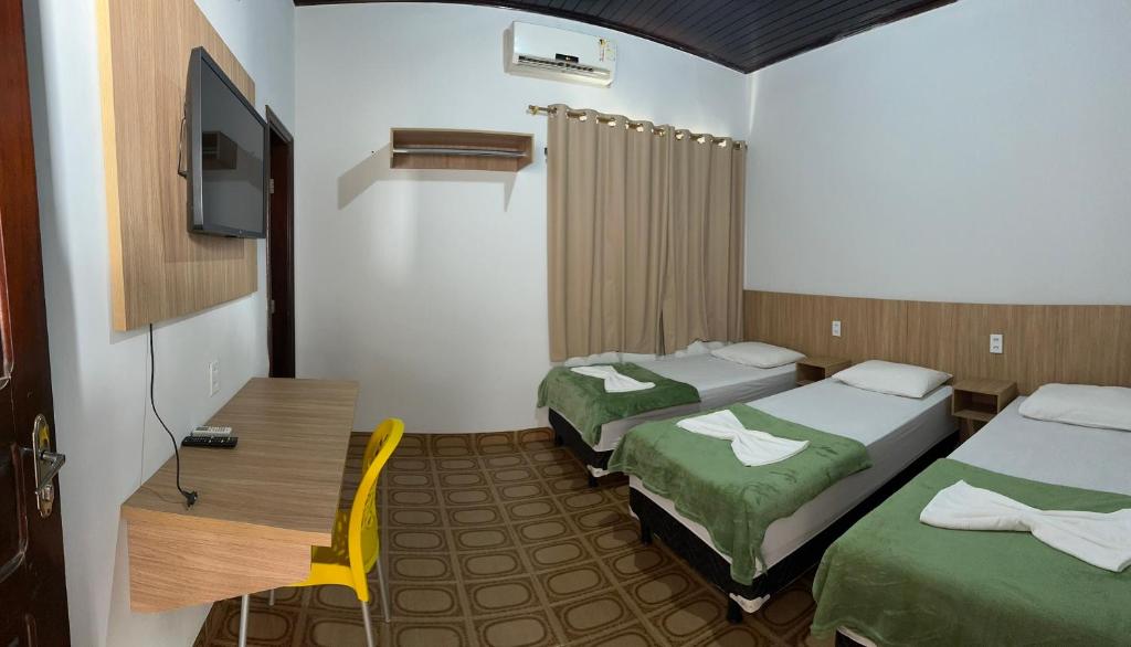 a hotel room with two beds and a television at Hotel Manarela in Imperatriz