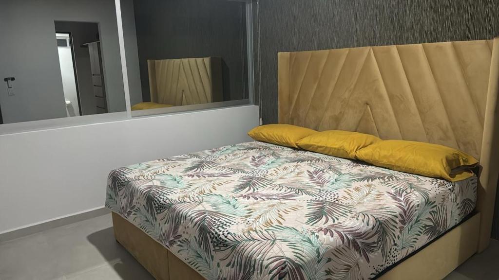 ein Bett mit zwei gelben Kissen und einem Spiegel in der Unterkunft Departamento en mazatlan bluue Lagoons in Mazatlán