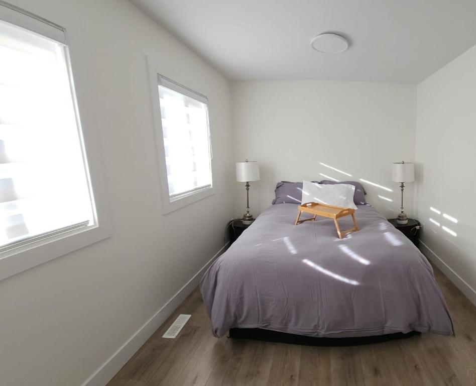 um quarto branco com uma cama e 2 janelas em 3bed 1 bath suite - Surrey Fleetwood em Surrey