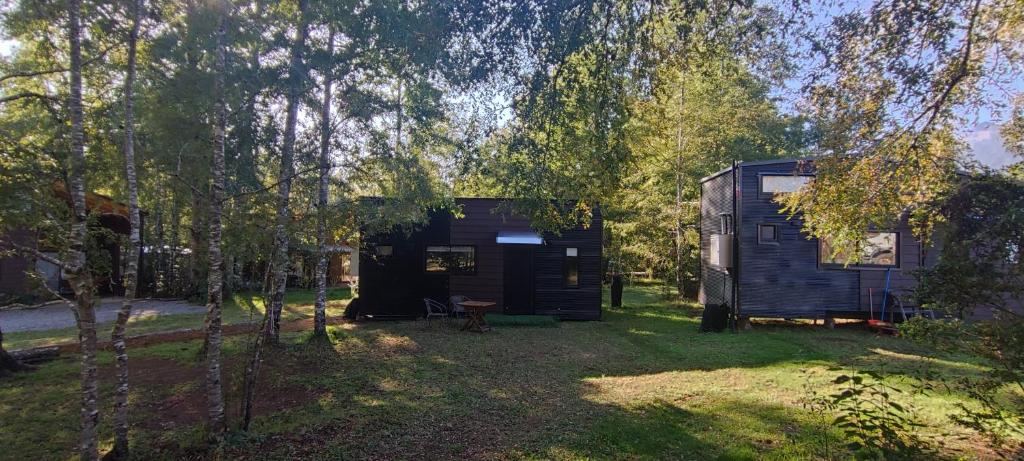 una casita negra en medio de un patio en Tiny house Alto bosque en Pucón