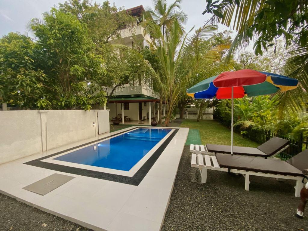 una piscina con panchina e ombrellone di Villa Araliya a Hikkaduwa