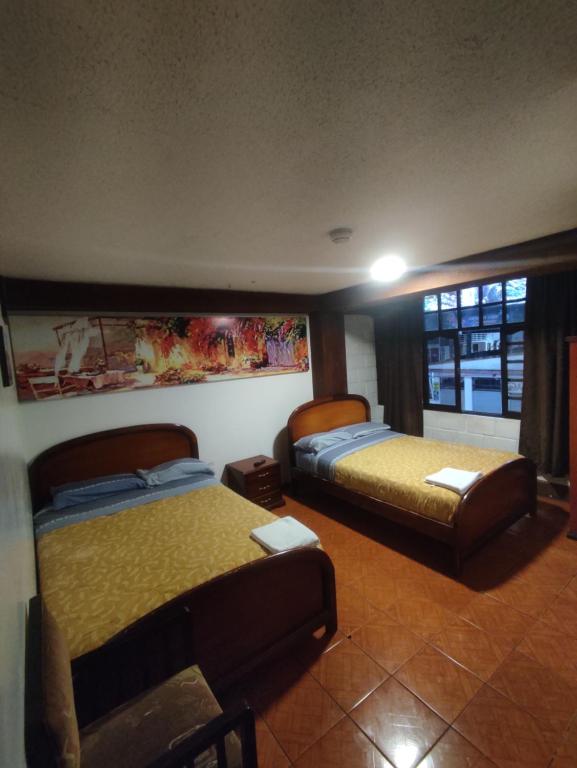 Cette chambre comprend 2 lits et une fenêtre. dans l'établissement HOSTAL WALDORF.EC, à Baños