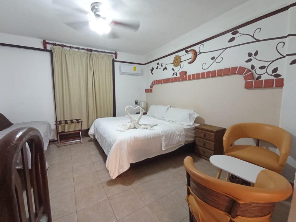 a bedroom with a white bed and a chair at Suites Fenicia in Playa del Carmen