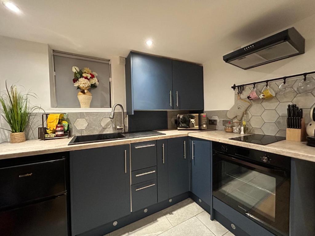 a kitchen with blue cabinets and a counter top at VOS Lodge Leeds UK in Hunslet