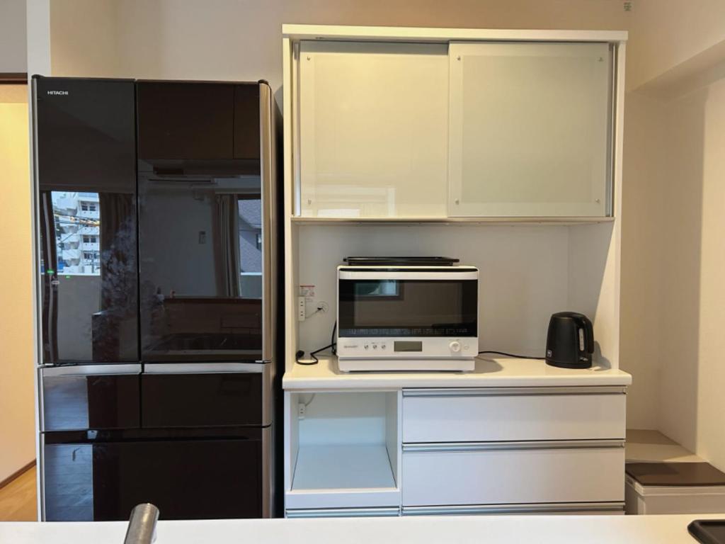 a kitchen with a microwave and a refrigerator at Jintai House in Hakata