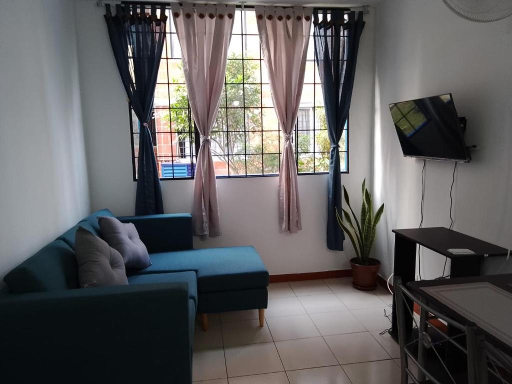a living room with a blue couch and two windows at Apartamento en Villavicencio in Villavicencio