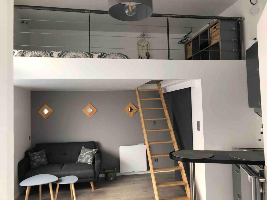Cette chambre comprend une mezzanine avec un canapé et une table. dans l'établissement Studio moderne à Clermont-Ferrand – 35 m² + Parking gratuit, à Clermont-Ferrand