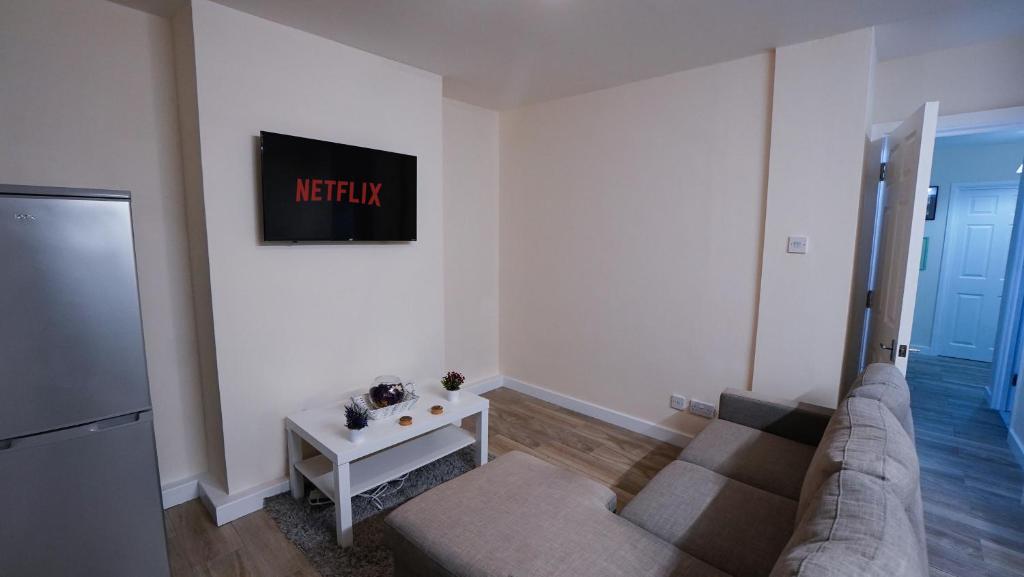 a living room with a couch and a tv on the wall at Luxury 2 Bed Apartment London Twickenham in Hounslow