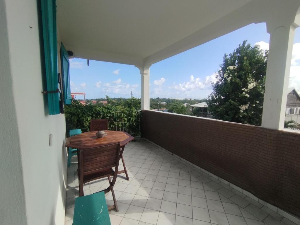 un patio con tavolo e sedie su un balcone di Ti' cocon des îles a Le Moule