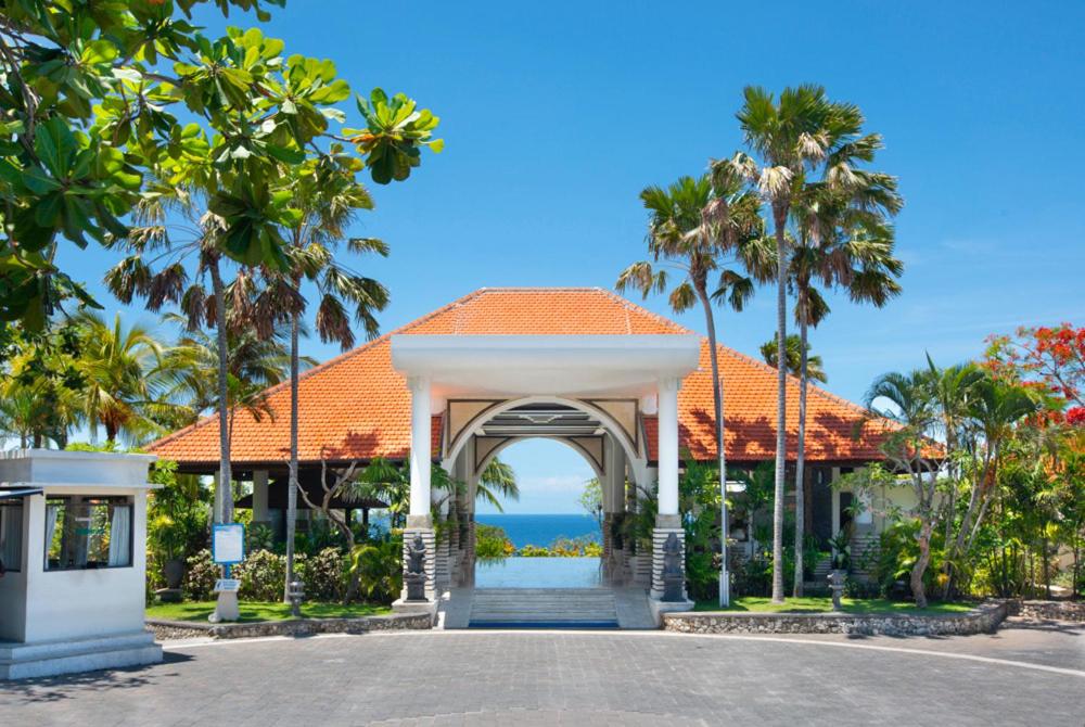 une porte menant à un complexe avec des palmiers et l'océan dans l'établissement Blue Point Resort and Spa, à Uluwatu