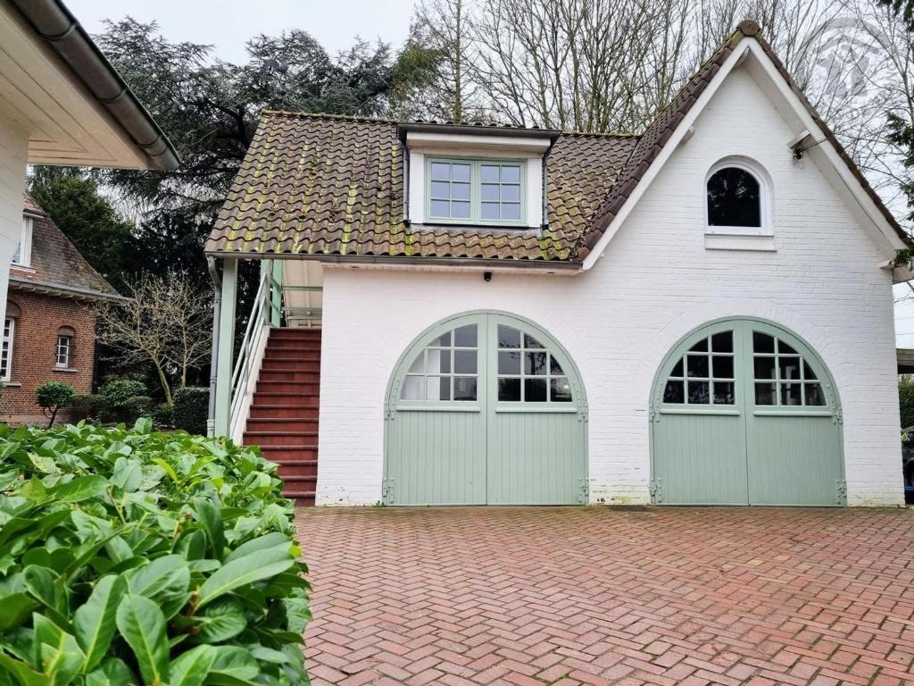 a house with green garage doors on a brick driveway at Gîte spacieux et moderne, à 12 km de Lille, avec toutes commodités, idéale pour une escapade tranquille - FR-1-510-208 in Linselles