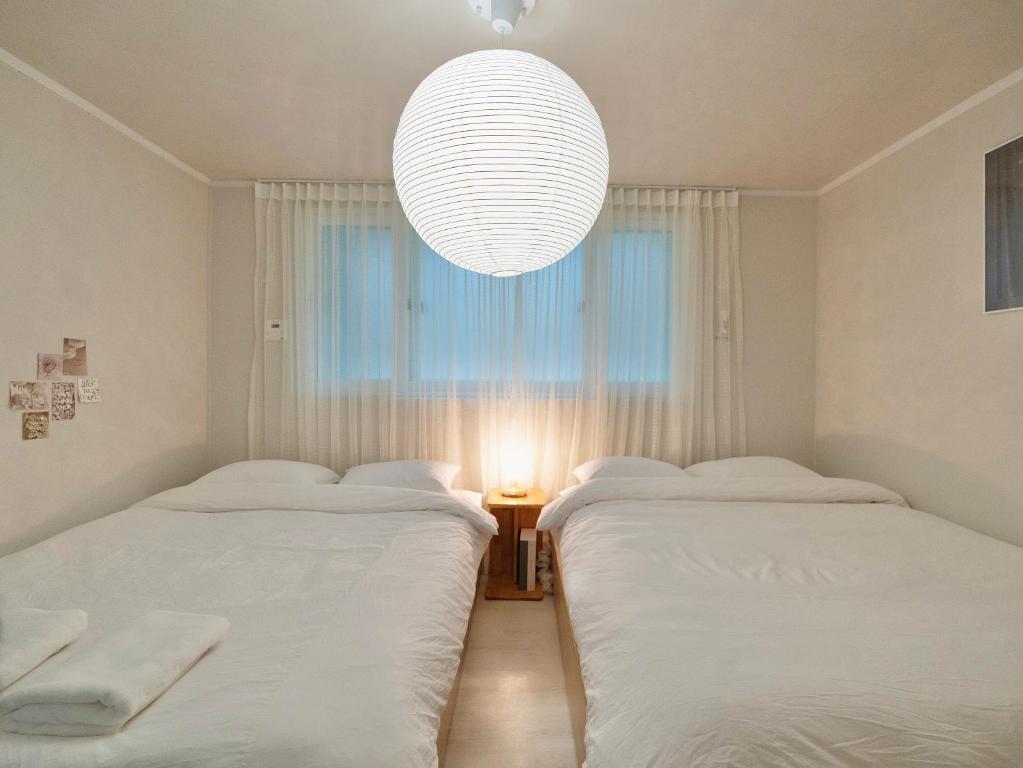 two beds in a room with a chandelier at Hygge - Urban Hideout with four comfort beds in Seoul