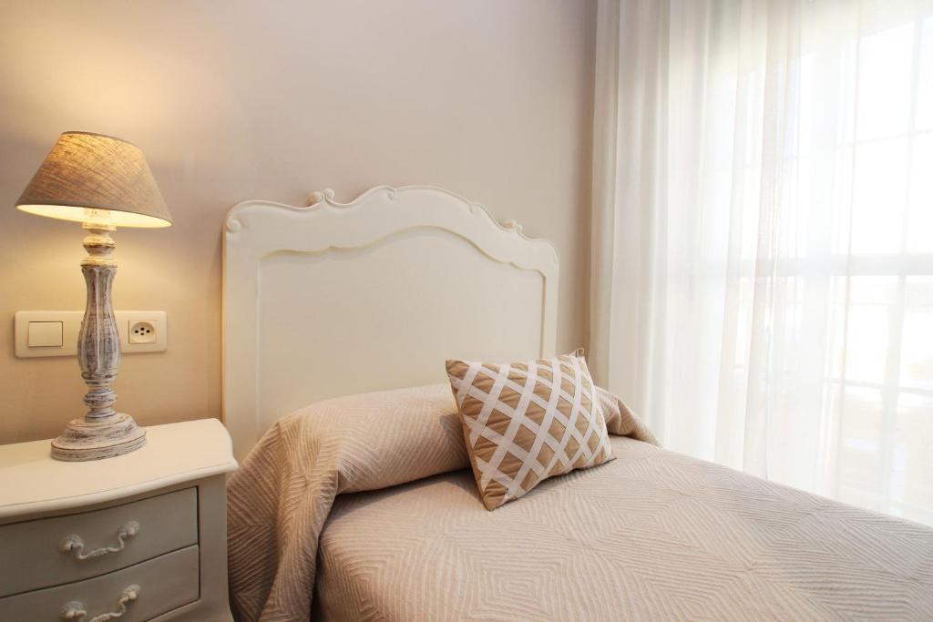 a bedroom with a bed with a lamp and a window at Hotel Maestranza in Seville