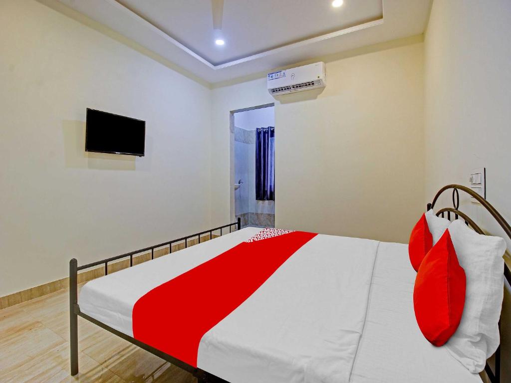 1 dormitorio con 1 cama con almohadas rojas y TV en OYO Flagship Hotel Vathsalya, en Warangal