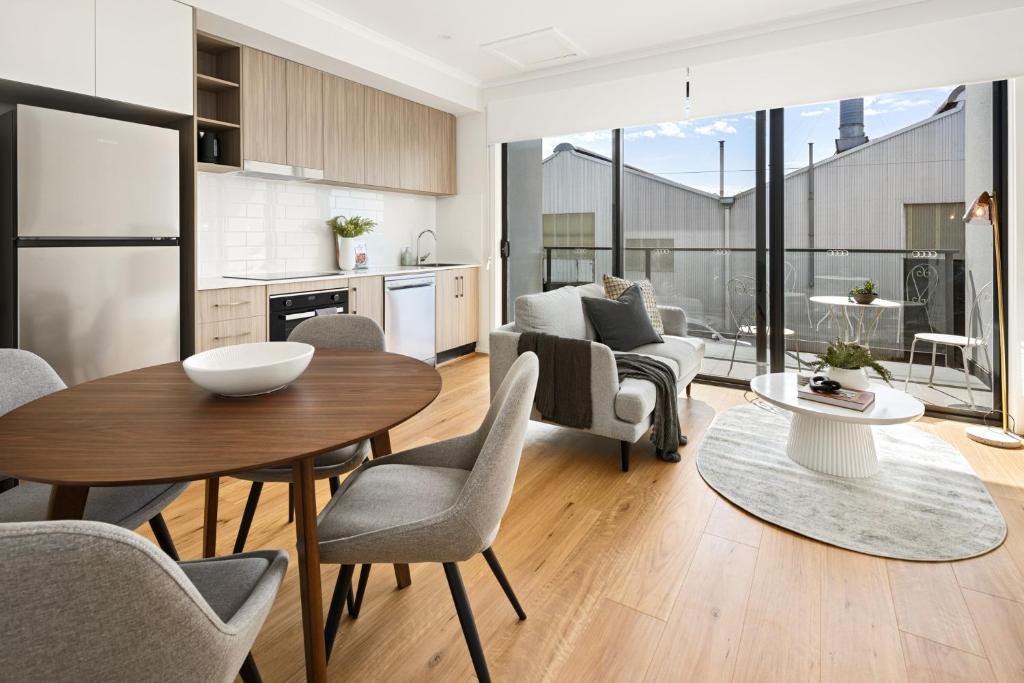 a kitchen and living room with a table and chairs at Clare St Apartments by Urban Rest in Port Adelaide