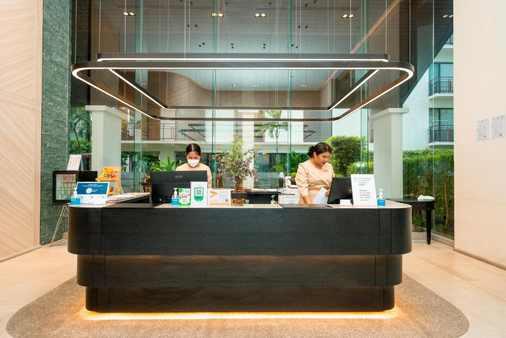 A polished reception desk sits beneath a striking geometric light fixture.