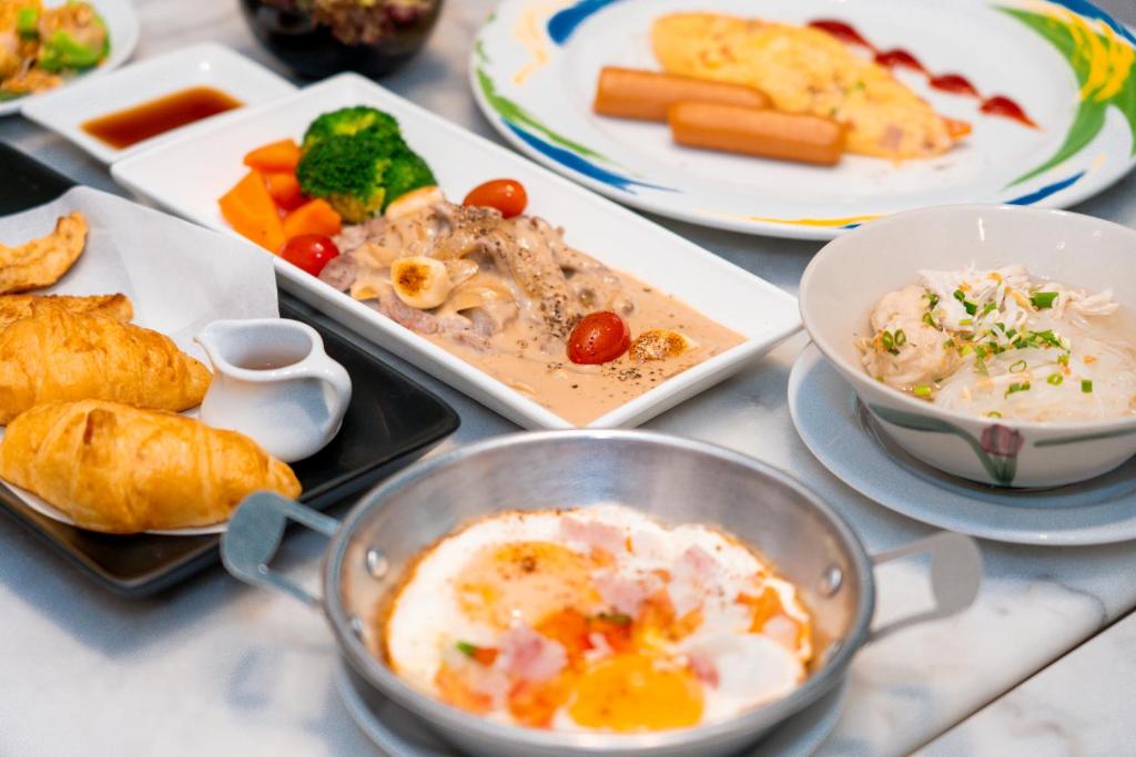 A close view of plated breakfast dishes including pastries, eggs, vegetables and a rice bowl.