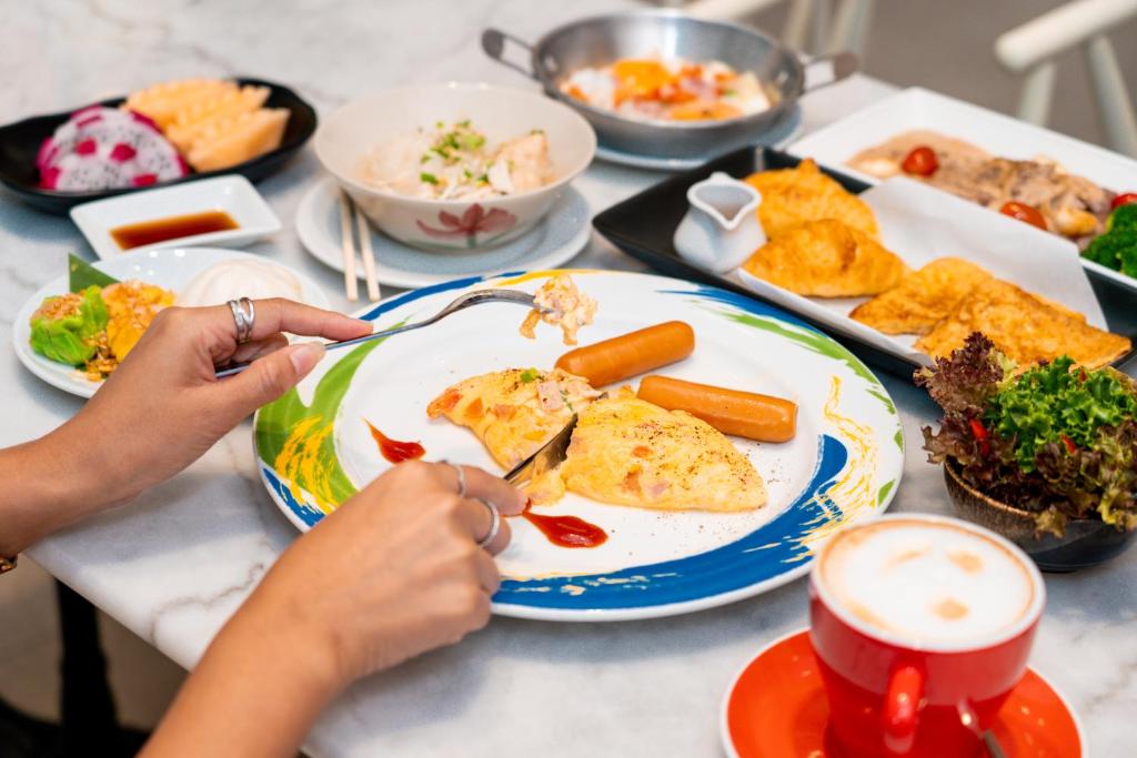 A diner cuts into a plated breakfast surrounded by pastries, fruit and other dishes.