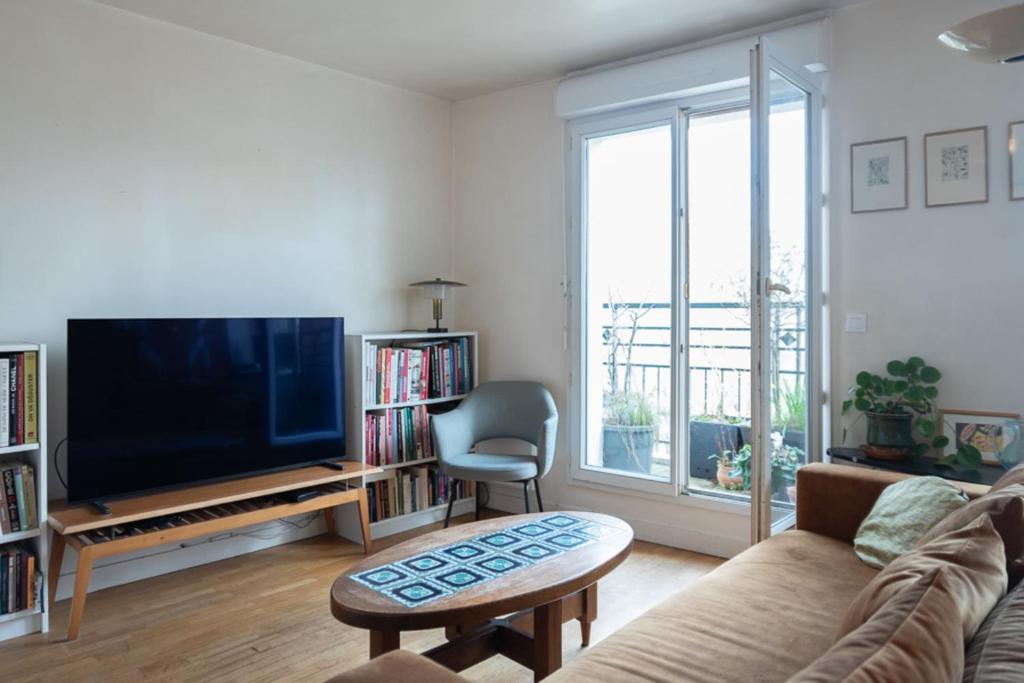 a living room with a couch and a tv at Luminous cocoon - view of Canal Saint-Martin in Paris
