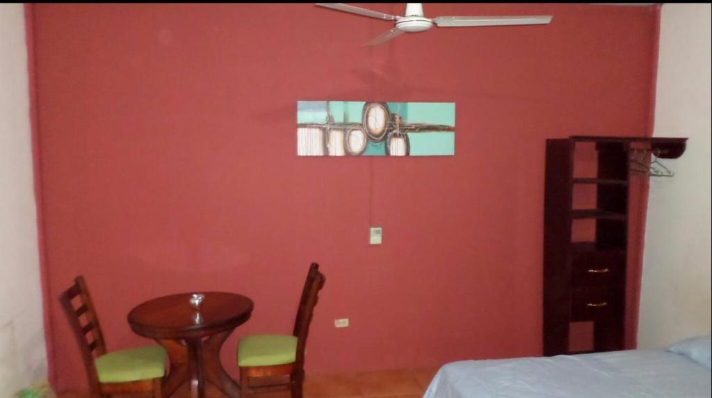 a room with a red wall with a table and chairs at 31 ave home stay in Managua