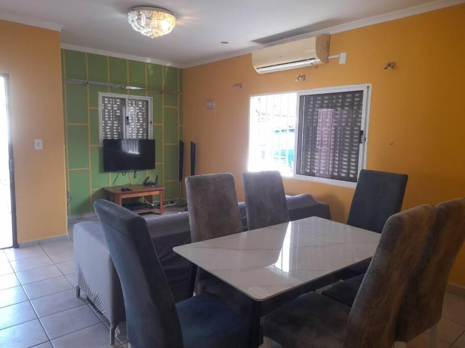 a dining room with a table and chairs and a television at Casa de Amor in Luanda