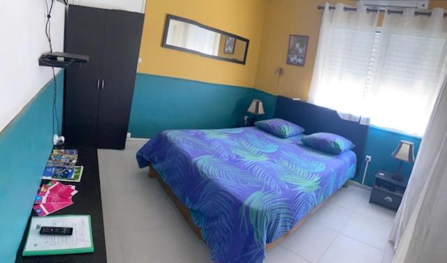 ein Schlafzimmer mit einem Bett mit einer blauen und gelben Wand in der Unterkunft Runappart974 in Saint-Louis