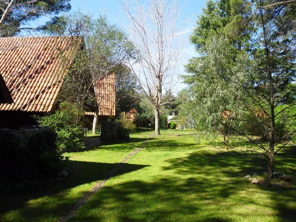 un patio con una casa y algunos árboles y hierba en Cabañas Ñuke Mapu en Villa Ventana