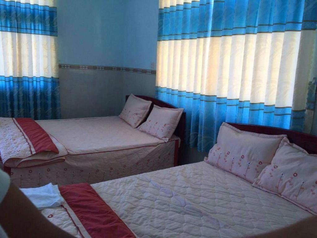2 łóżka w pokoju z niebieskimi ścianami i oknami w obiekcie HOA BỈ NGẠN w Ho Chi Minh