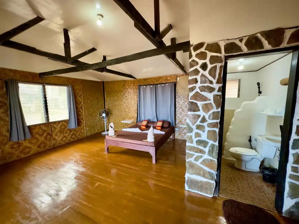 sala de estar con sofá y pared de piedra en Playa del Fuego Camiguin Beach Hostel & Resort, en Mambajao