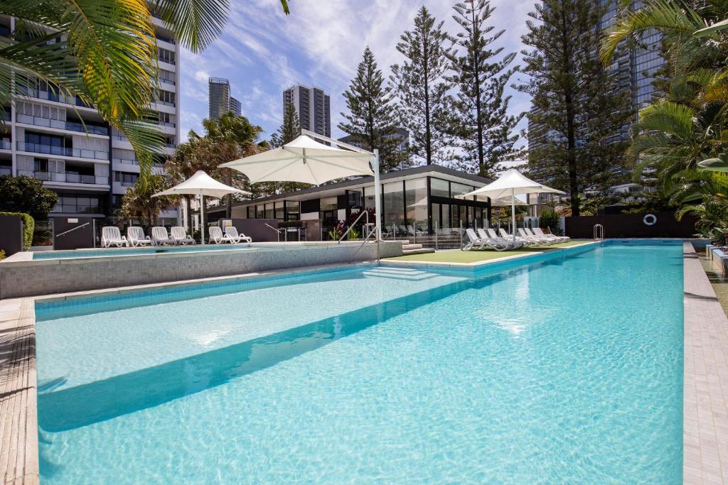 una gran piscina con sillas y sombrillas en Ultra Broadbeach, en Gold Coast