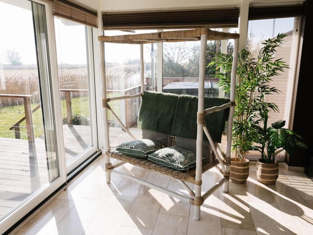 een veranda met een stoel en een aantal planten bij Holiday home Zanddrijver in Makkum