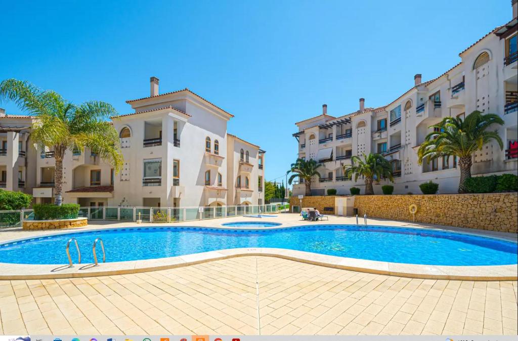 a swimming pool in front of some buildings at E041 Apartment Albir in L’Alfàs del Pi
