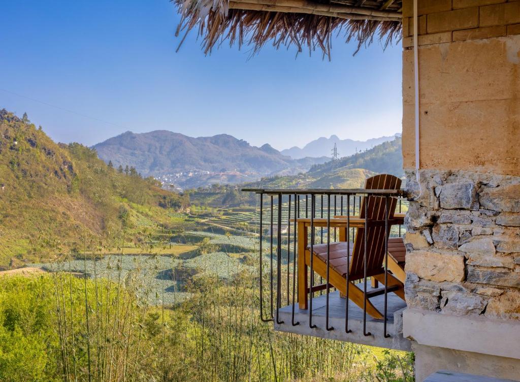 een stoel op een balkon met uitzicht op een vallei bij Sapaxa Spring Garden Ecolodge in Sa Pa