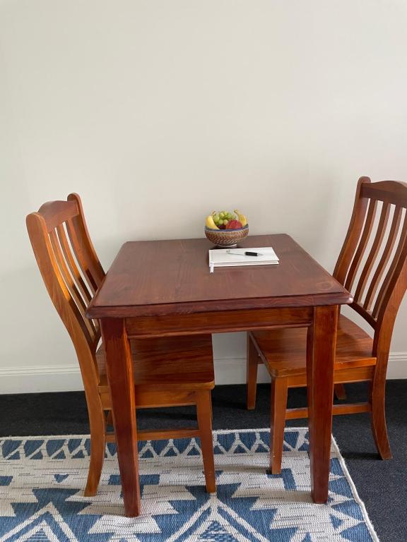 een houten tafel met 2 stoelen en een fruitschaal bij Violet Cottage in the City in Hobart