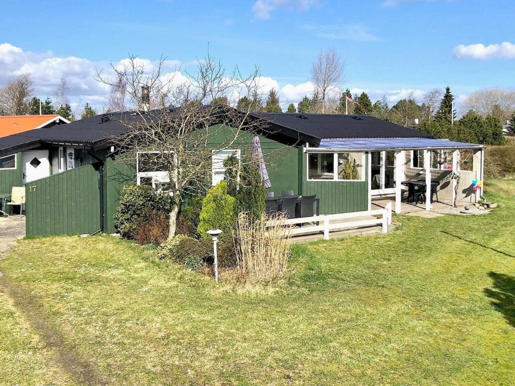 a green house with a black roof on a yard at Holiday home Middelfart IV in Middelfart